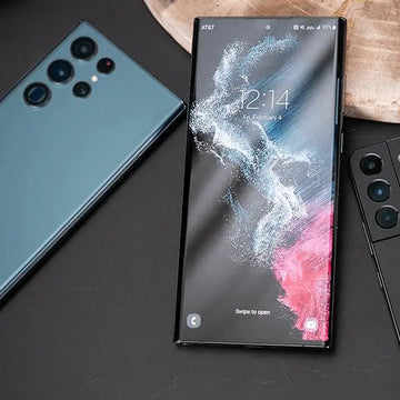 Three smartphones on a dark surface with a wooden background